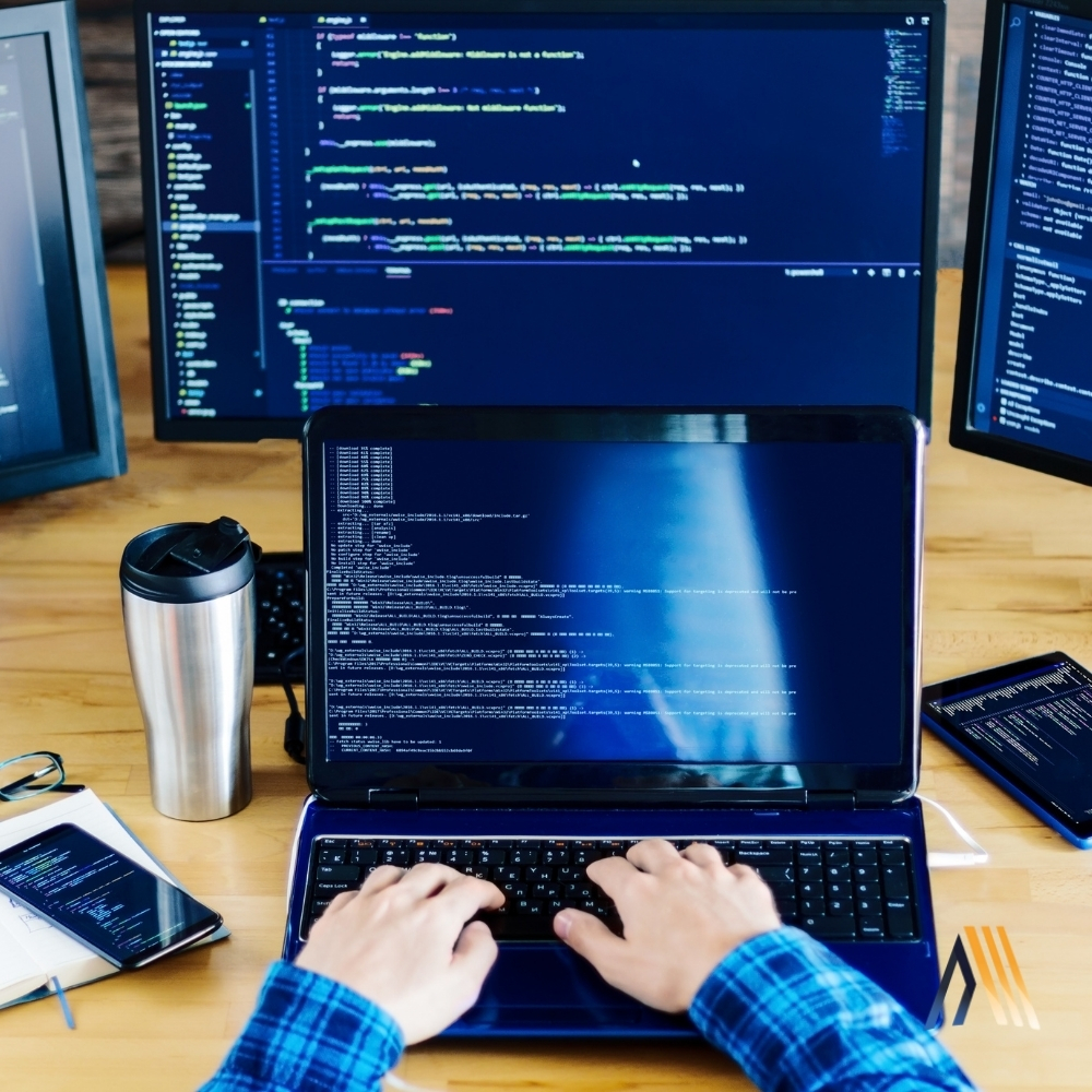 Programador trabajando en múltiples pantallas de código